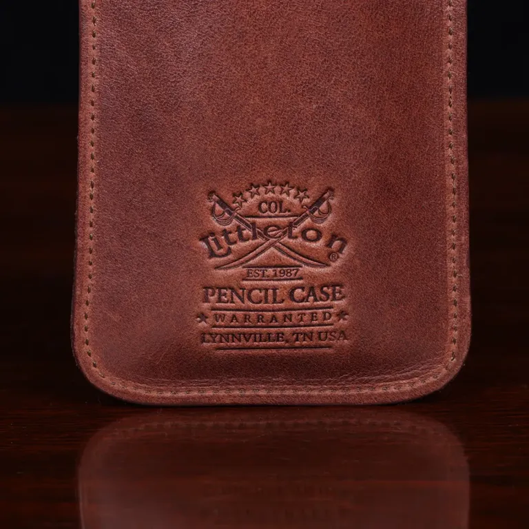 leather pencil case on wooden table - view of logo