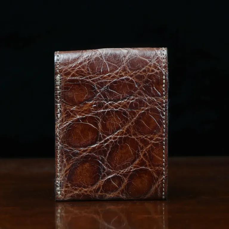 Front pocket wallet with flap in brown American Alligator - back view - 001 - on wood table with a dark background