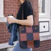 Woman carrying coffee, jacket and Steeplechase Tote featuring alternating full-grain leather squares