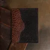 dark brown leather wallet with alligator trim showing forn on wood surface