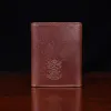 no 1 trifold wallet in brown steerhide on a wooden table with a dark background - back view