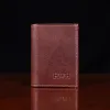no 1 trifold wallet in brown steerhide on a wooden table with a dark background - front view