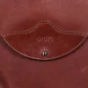 No. 22B Derby Handbag in Vintage Brown on a wood table with a dark background - front view of initials